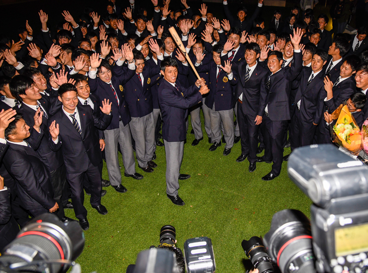  Ryosuke Tatsumi holds a baseball bat surrounded by Ritsumeikan club members - cameras in foreground