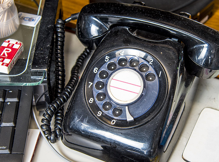 A round dial black telephone sitting on Professor French's desk with a Ritsumeikan eraser