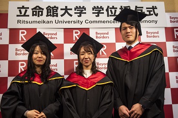 Three students stand in front of a photo board outside the venue