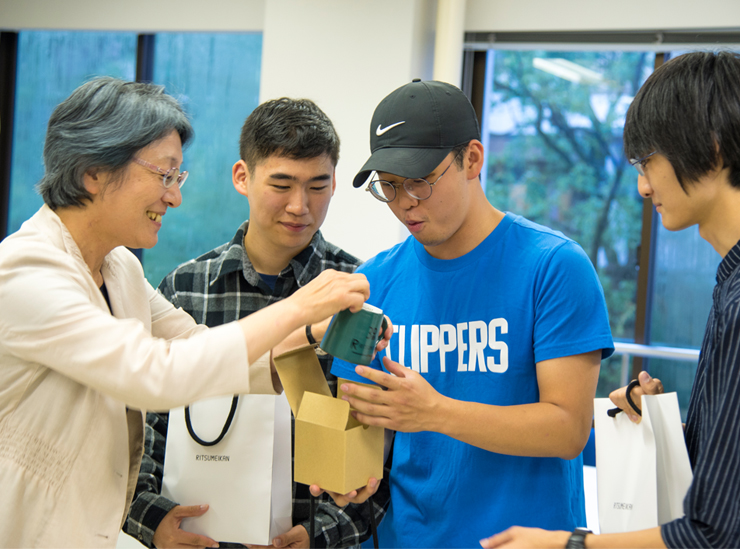 Dean Kawamura smiles whilst point out that the farewell gift of a mug has been personalized on the underneath with the year and name of student