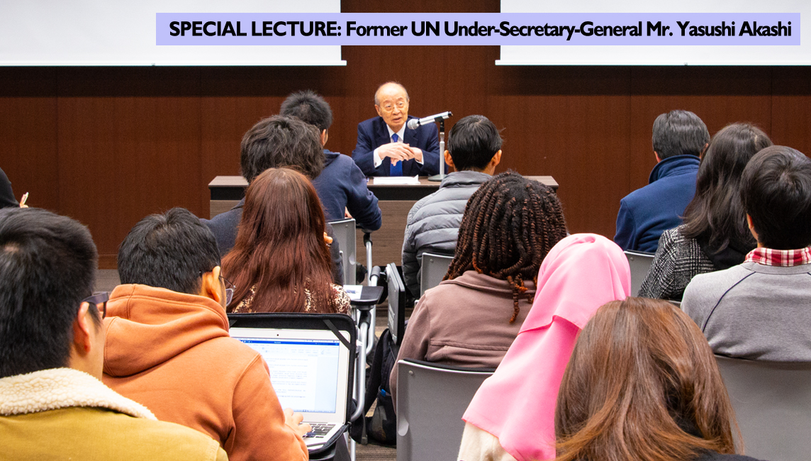 Former UN Under-Secretary-General Mr. Yasushi Akashi sits at a desk addressing a room full of students