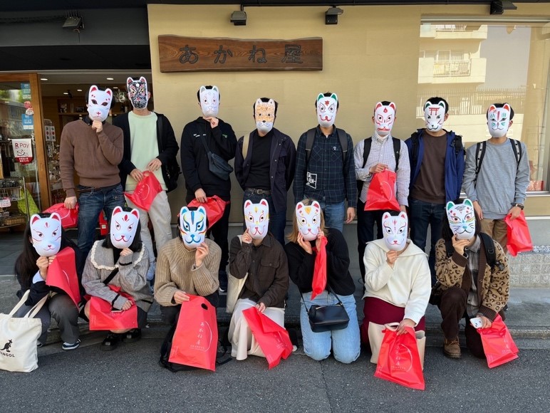 15 students standing for a group photo wearing their newly finished traditional masks