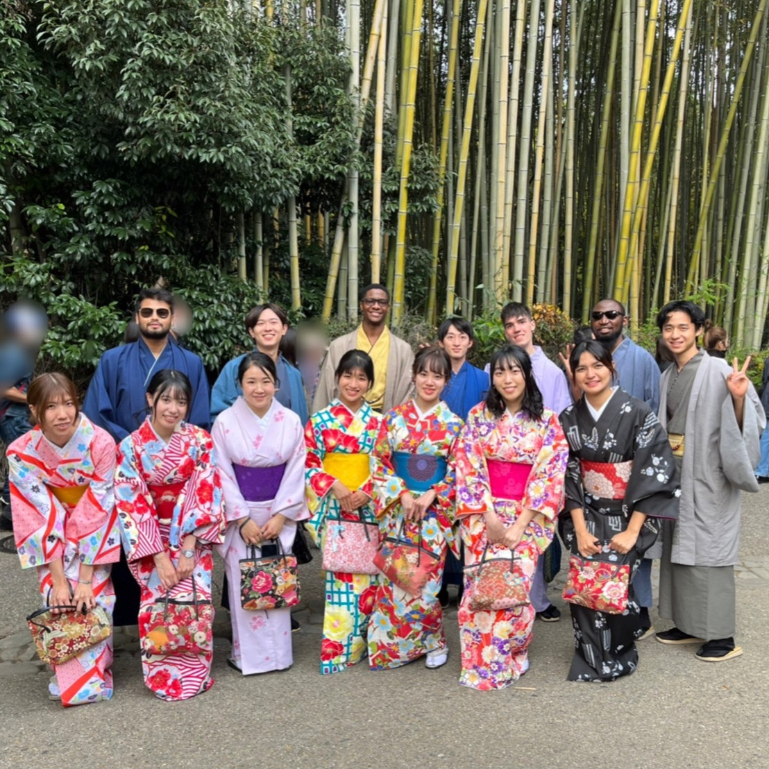 Students dressed in kimonos smile for a group photo in front of a bamboo forest