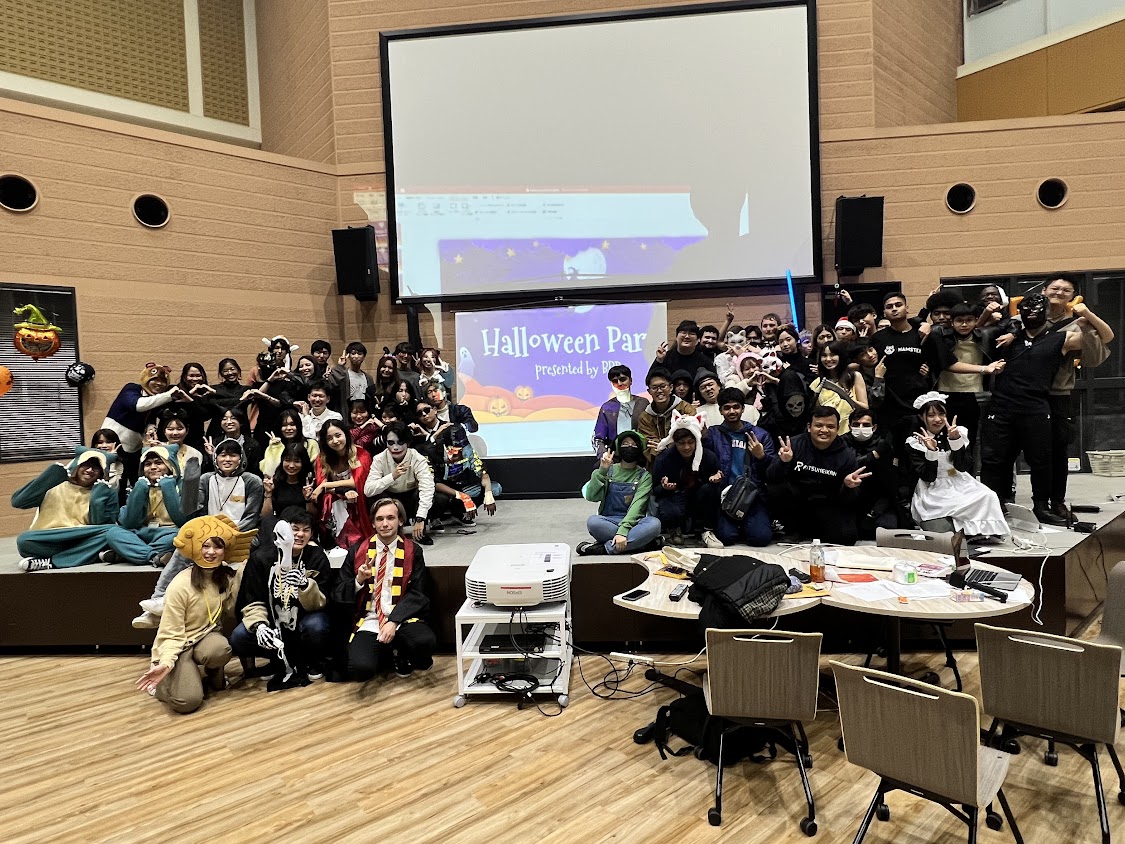 Group photo of students dressed for Halloween, gathered on top of a stage