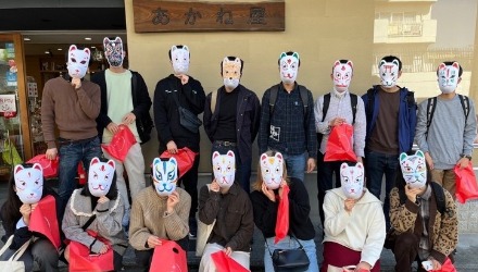 15 students standing for a group photo wearing their newly finished traditional masks