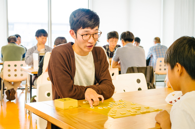 Ritsumeikan University College Festival - a student plays the traditional game shogi with a local child